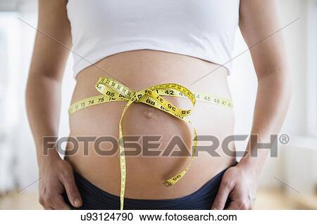Mid section of pregnant woman with tape measure tied up on her belly View Large Photo Image Stock Image - Mid section of pregnant woman with tape measure tied up on her belly. Fotosearch