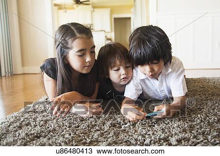 Stock Image - Mixed aged kids playing mobile phone game. Fotosearch