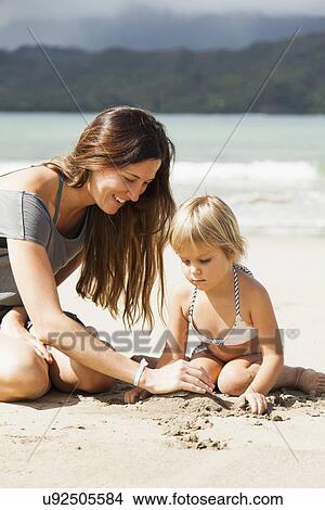 Picture - Mother playing with daughter (2-3) on beach. Fotosearch