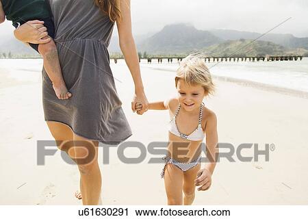Stock Image - Mother walking with daughters (6-11 months, 2-3) on beach. Fotosearch