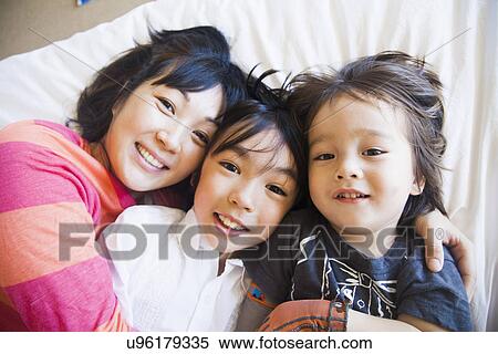 Mother with children cuddling on bed View Large Photo Image Stock Photography - Mother with children cuddling on bed. Fotosearch