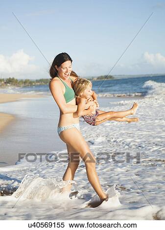 Stock Photography - Mother with daughter (2-3) playing on beach. Fotosearch
