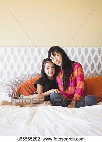 Mother with daughter (8-9) sitting on bed View Large Photo Image Stock Image - Mother with daughter (8-9) sitting on bed. Fotosearch