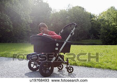 Stock Image - Mother with pram in park. Fotosearch
