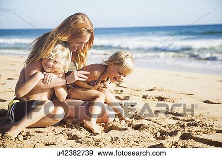 Stock Photo - Mother with son (6-7) and daughter (2-3) on beach. Fotosearch