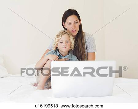 Stock Photo - Mother with son (6-7) using laptop. Fotosearch