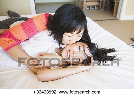 Stock Image - Mother with son (8-9) cuddling on bed. Fotosearch