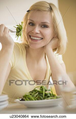 Picture - Portrait of cheerful woman eating salad. Fotosearch