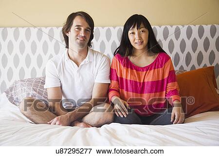 Portrait of couple sitting on bed View Large Photo Image Stock Photo - Portrait of couple sitting on bed. Fotosearch