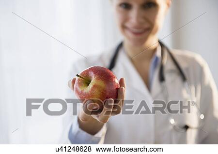 Portrait of doctor giving apple View Large Photo Image Stock Photo - Portrait of doctor giving apple. Fotosearch