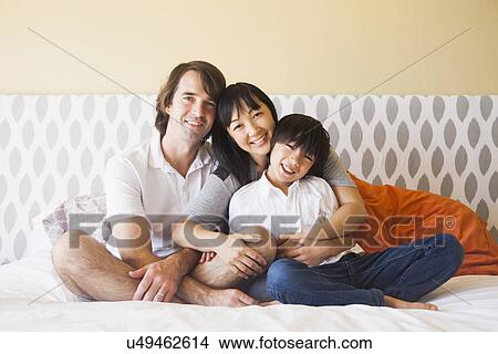 Portrait of family sitting on bed View Large Photo Image Picture - Portrait of family sitting on bed. Fotosearch