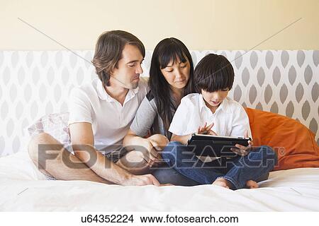 Portrait of family sitting on bed View Large Photo Image Picture - Portrait of family sitting on bed. Fotosearch
