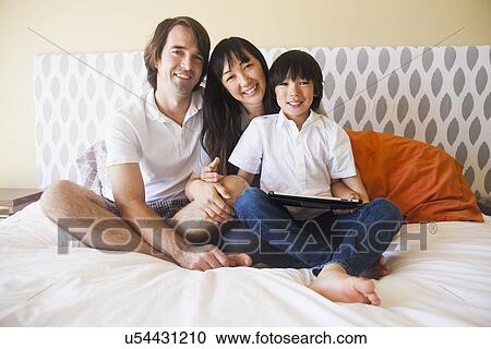 Portrait of family sitting on bed View Large Photo Image Stock Image - Portrait of family sitting on bed. Fotosearch