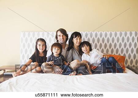 Portrait of family sitting on bed View Large Photo Image Stock Image - Portrait of family sitting on bed. Fotosearch