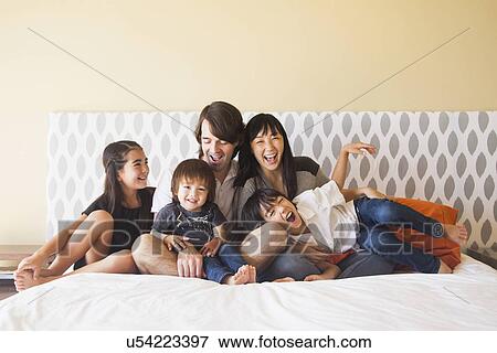 Portrait of family sitting on bed View Large Photo Image Stock Photo - Portrait of family sitting on bed. Fotosearch