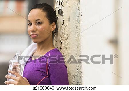 Stock Image - Portrait of female jogger with water bottle. Fotosearch