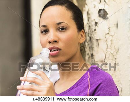 Stock Image - Portrait of female jogger with water bottle. Fotosearch