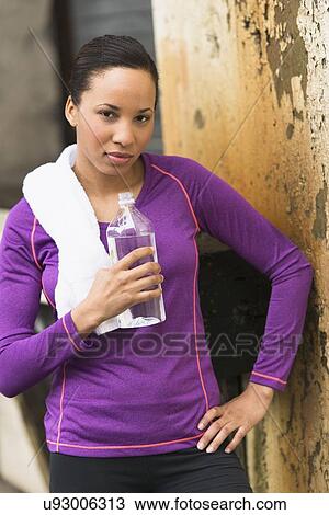 Stock Image - Portrait of female jogger with water bottle. Fotosearch