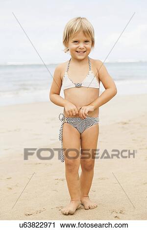 Stock Image - Portrait of girl (2-3) standing on beach. Fotosearch