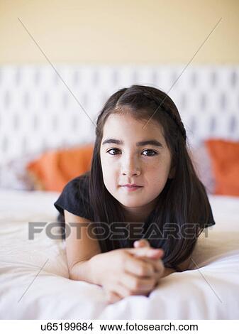 Portrait of girl (8-9) laying on bed View Large Photo Image Picture - Portrait of girl (8-9) laying on bed. Fotosearch