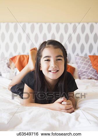 Portrait of girl (8-9) laying on bed View Large Photo Image Stock Photograph - Portrait of girl (8-9) laying on bed. Fotosearch