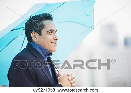 Portrait of man holding blue umbrella View Large Photo Image Stock Photo - Portrait of man holding blue umbrella. Fotosearch