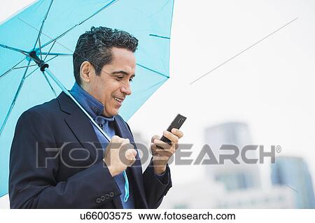 Portrait of man holding blue umbrella and using mobile phone View Large Photo Image Stock Photography - Portrait of man holding blue umbrella and using mobile phone. Fotosearch