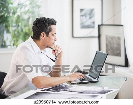 Picture - Portrait of man in his photography studio using laptop. Fotosearch