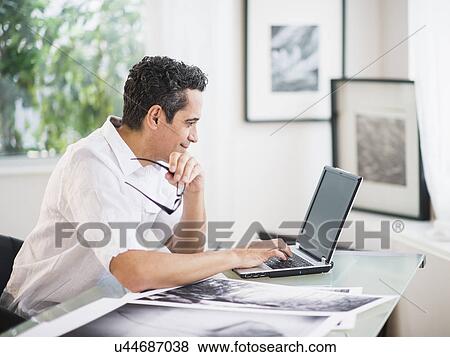Stock Photo - Portrait of man in his photography studio using laptop. Fotosearch