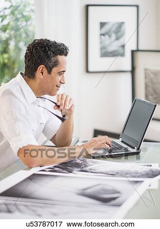 Stock Photo - Portrait of man in his photography studio using laptop. Fotosearch