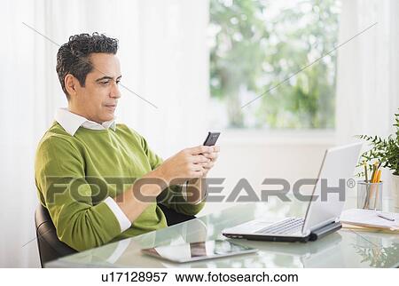 Portrait of man using mobile phone at desk View Large Photo Image Stock Photo - Portrait of man using mobile phone at desk. Fotosearch