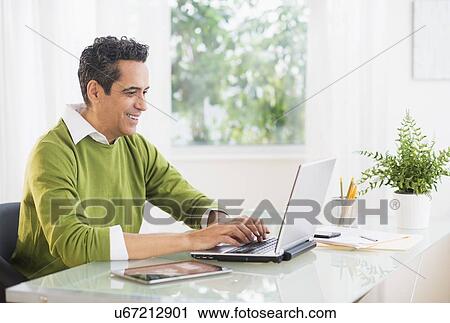 Stock Image - Portrait of man working on laptop at home. Fotosearch