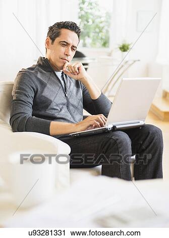 Stock Image - Portrait of man working on laptop at home. Fotosearch