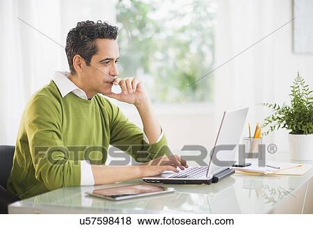 Portrait of man working on laptop at home View Large Photo Image Stock Photo - Portrait of man working on laptop at home. Fotosearch