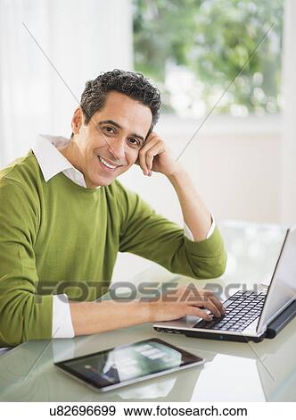 Portrait of man working on laptop at home View Large Photo Image Stock Photo - Portrait of man working on laptop at home. Fotosearch