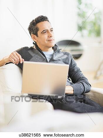 Stock Photography - Portrait of man working on laptop at home. Fotosearch