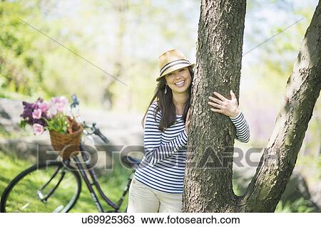 Stock Image - Portrait of mid adult woman embracing tree. Fotosearch