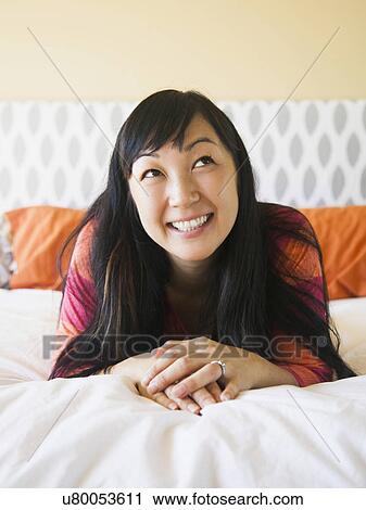 Portrait of mid adult woman laying on bed View Large Photo Image Stock Image - Portrait of mid adult woman laying on bed. Fotosearch