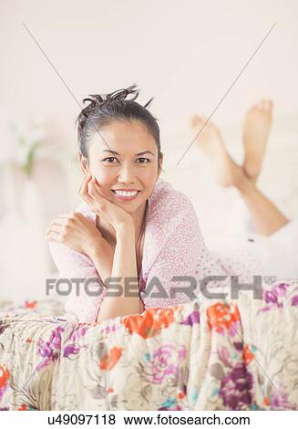 Stock Photo - Portrait of mid adult woman lying on bed. Fotosearch