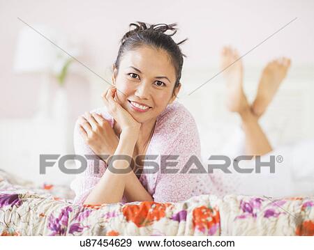 Stock Photo - Portrait of mid adult woman lying on bed. Fotosearch