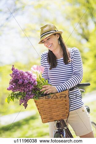Stock Photo - Portrait of mid adult woman riding bicycle. Fotosearch