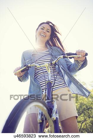 Stock Image - Portrait of mid adult woman with bicycle. Fotosearch