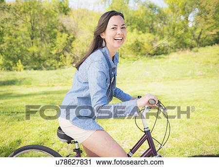 Stock Image - Portrait of mid adult woman with bicycle. Fotosearch