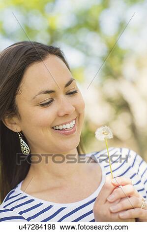 Stock Photo - Portrait of mid adult woman with dandelion. Fotosearch