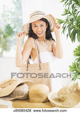 Portrait of mid adult women trying on straw hat View Large Photo Image Stock Photo - Portrait of mid adult women trying on straw hat. Fotosearch