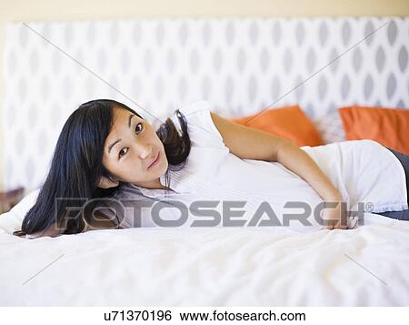 Stock Photograph - Portrait of pregnant woman laying on bed. Fotosearch