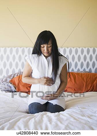 Portrait of pregnant woman sitting on bed View Large Photo Image Stock Image - Portrait of pregnant woman sitting on bed. Fotosearch