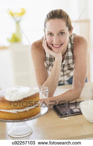 Stock Image - Portrait of woman using tablet pc in kitchen. Fotosearch