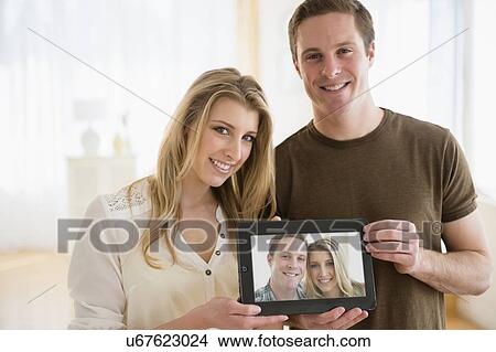 Portrait of young couple holding their picture View Large Photo Image Picture - Portrait of young couple holding their picture. Fotosearch