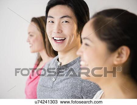 Portrait of young man standing between young women View Large Photo Image Stock Image - Portrait of young man standing between young women. Fotosearch
